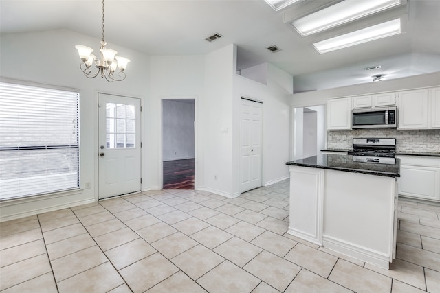 kitchen featuring vaulted ceiling, a chandelier, appliances with stainless steel finishes, white cabinets, and decorative light fixtures