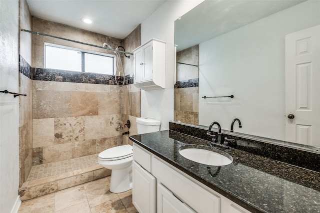 bathroom with a tile shower, vanity, and toilet