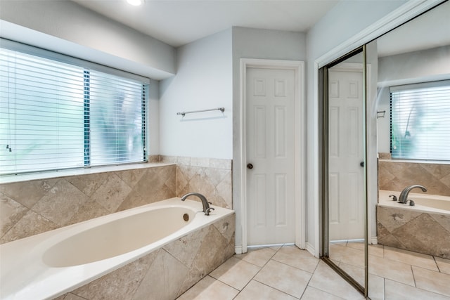 bathroom featuring tiled tub, tile patterned floors, and plenty of natural light