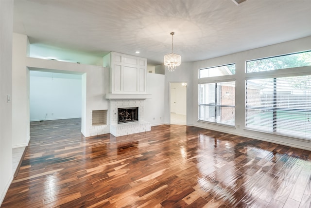 unfurnished living room with hardwood / wood-style floors, an inviting chandelier, and a fireplace