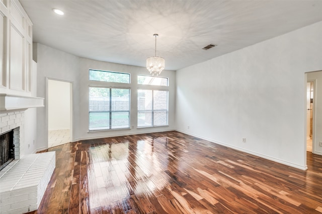 unfurnished living room featuring a fireplace, a chandelier, and dark hardwood / wood-style floors