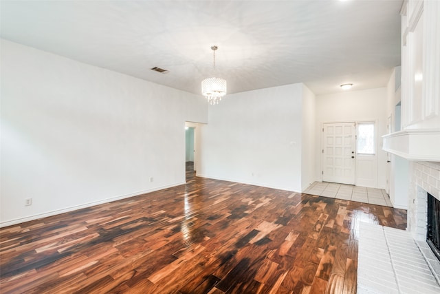 unfurnished living room with light hardwood / wood-style floors, a chandelier, and a fireplace