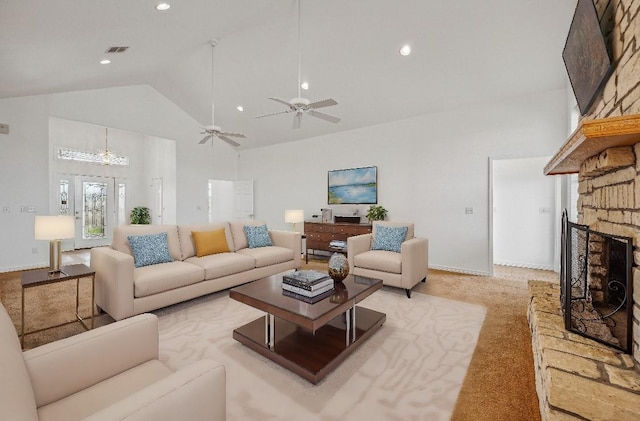 unfurnished living room with a stone fireplace, light carpet, high vaulted ceiling, and ceiling fan with notable chandelier