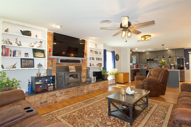 living room with hardwood / wood-style flooring, ceiling fan, and a wood stove