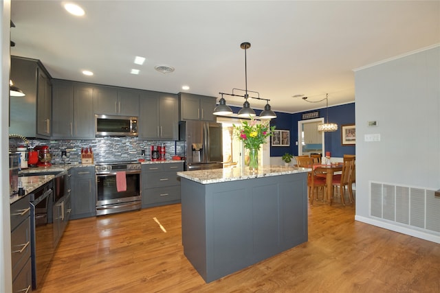 kitchen featuring light stone countertops, a center island, stainless steel appliances, light hardwood / wood-style flooring, and pendant lighting