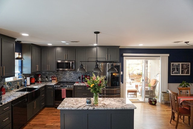 kitchen featuring stainless steel appliances, a kitchen island, hanging light fixtures, and light hardwood / wood-style flooring