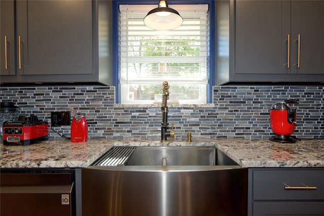 kitchen with tasteful backsplash, gray cabinetry, light stone counters, and sink