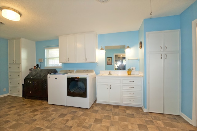 clothes washing area with separate washer and dryer, sink, cabinets, and a textured ceiling