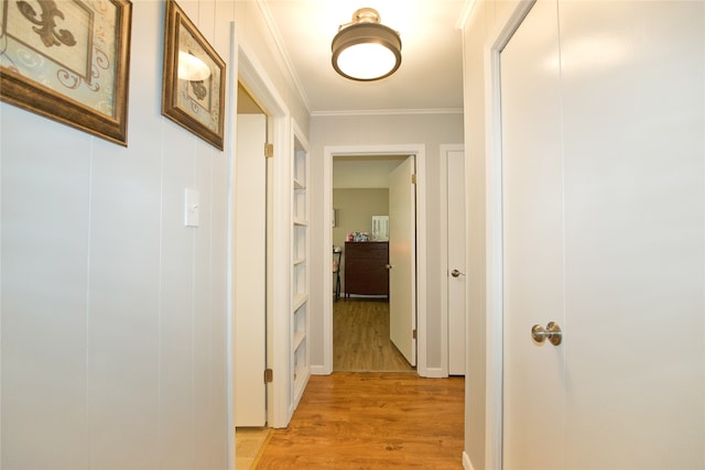 corridor with light hardwood / wood-style flooring and ornamental molding