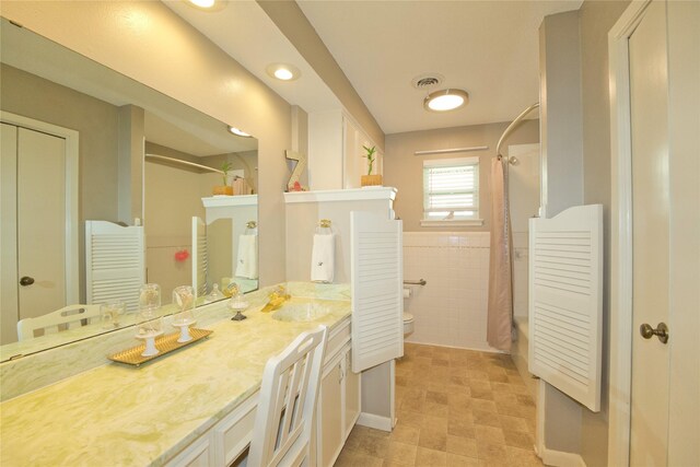 full bathroom with vanity, shower / bathtub combination with curtain, tile walls, and toilet