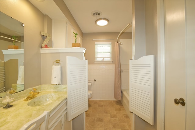 full bathroom featuring shower / bath combo, vanity, toilet, and tile walls