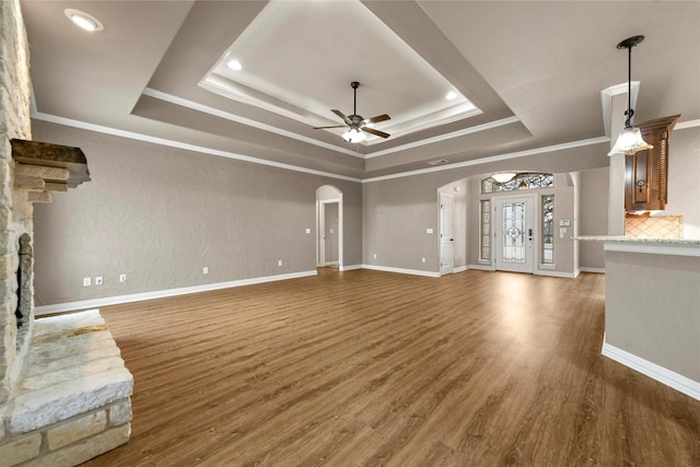 unfurnished living room with dark hardwood / wood-style floors, ceiling fan, and a raised ceiling