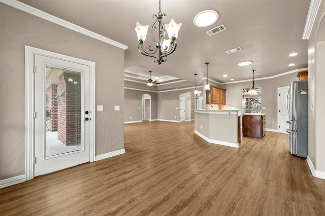 kitchen with decorative light fixtures, crown molding, dark wood-type flooring, and stainless steel refrigerator