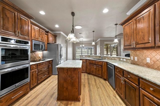 kitchen featuring hanging light fixtures, light hardwood / wood-style flooring, appliances with stainless steel finishes, a kitchen island, and kitchen peninsula