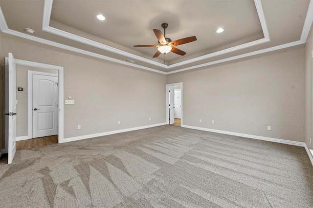 carpeted spare room with a raised ceiling, ceiling fan, and ornamental molding