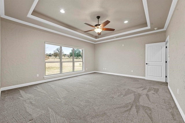 carpeted empty room featuring a tray ceiling, ceiling fan, and ornamental molding