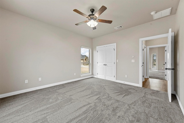 unfurnished bedroom featuring multiple windows, carpet floors, a closet, and ceiling fan