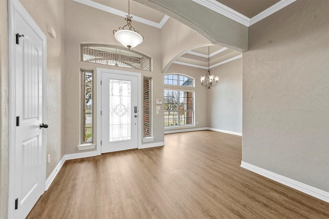 entrance foyer with hardwood / wood-style floors, an inviting chandelier, and ornamental molding