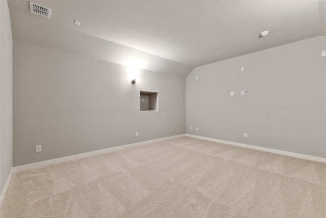 spare room with light carpet and lofted ceiling