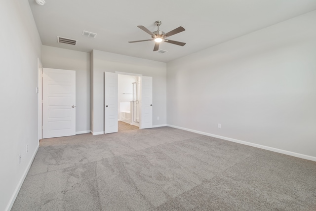 unfurnished bedroom featuring ceiling fan, light carpet, and ensuite bath