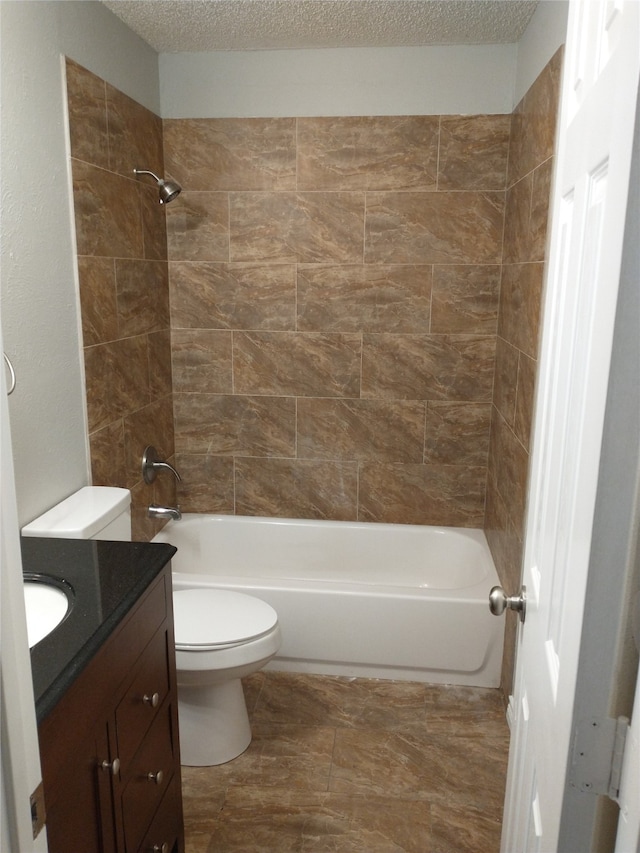 full bathroom with vanity, toilet, a textured ceiling, and tiled shower / bath combo