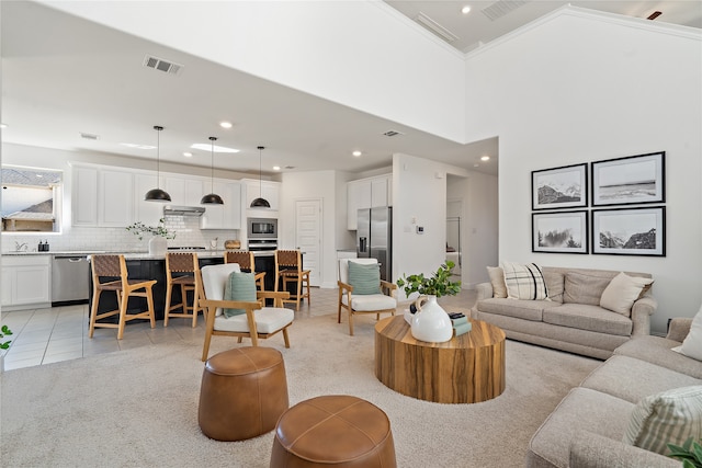 living room featuring a towering ceiling, light tile patterned floors, and ornamental molding