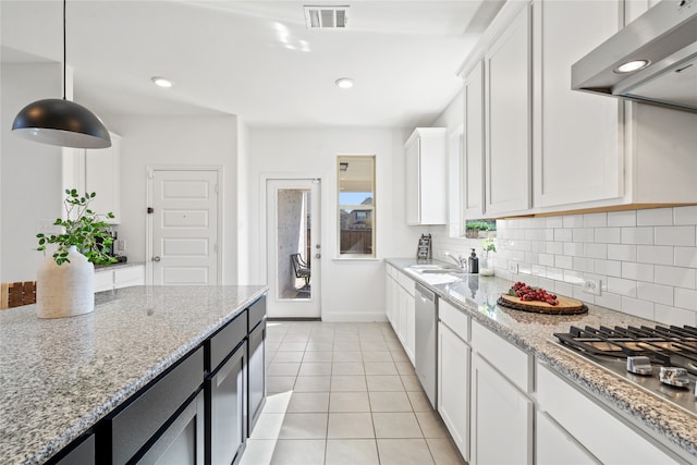 kitchen featuring white cabinetry, stainless steel appliances, light stone counters, decorative light fixtures, and exhaust hood