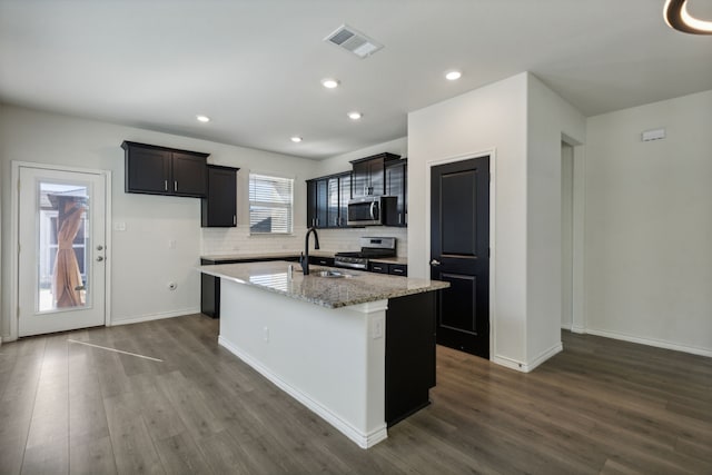 kitchen with dark wood-type flooring, stainless steel appliances, a center island with sink, and sink