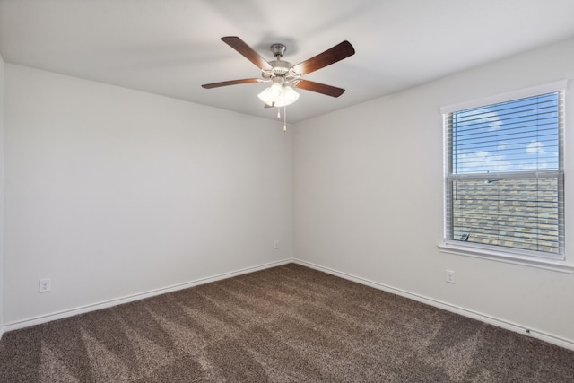 spare room featuring dark colored carpet and ceiling fan