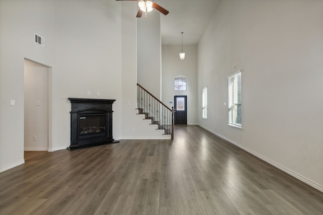 unfurnished living room featuring a high ceiling, dark hardwood / wood-style flooring, and ceiling fan