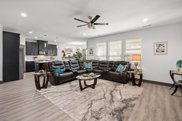 living room featuring light hardwood / wood-style floors and ceiling fan with notable chandelier