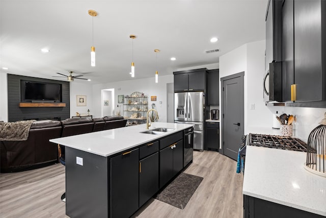 kitchen featuring a kitchen island with sink, sink, hanging light fixtures, light hardwood / wood-style floors, and stainless steel appliances