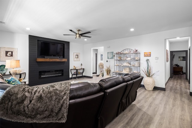 living room featuring ceiling fan, light hardwood / wood-style floors, and a fireplace