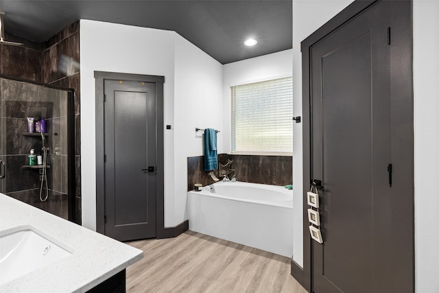 bathroom featuring hardwood / wood-style floors, vanity, and shower with separate bathtub