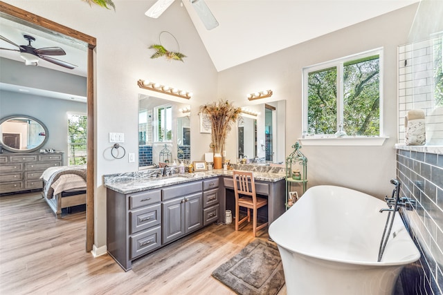 bathroom with a washtub, hardwood / wood-style floors, vanity, and vaulted ceiling