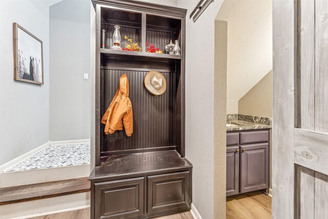 mudroom with light wood-type flooring and vaulted ceiling