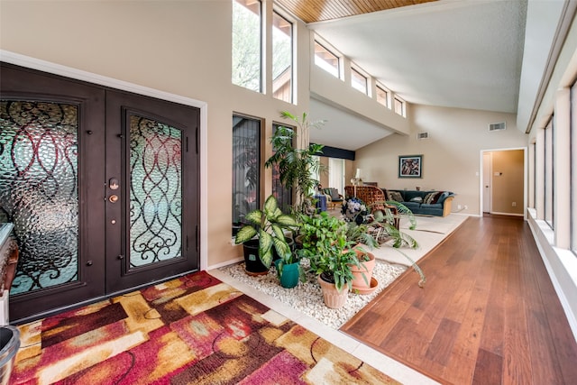 entrance foyer with hardwood / wood-style floors, high vaulted ceiling, and french doors