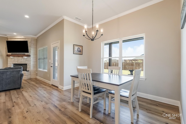 dining space with a fireplace, ornamental molding, hardwood / wood-style flooring, and a healthy amount of sunlight