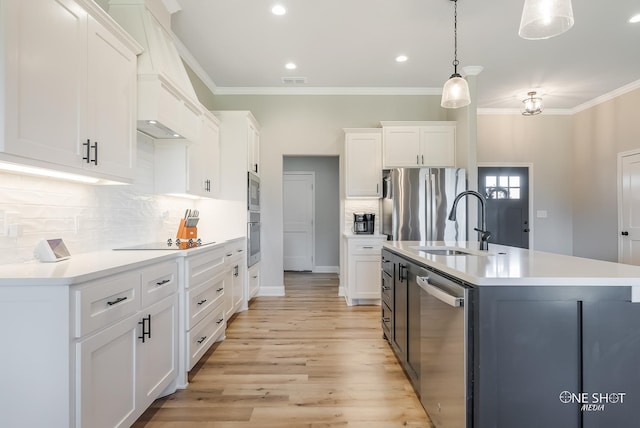 kitchen featuring white cabinets, decorative backsplash, hanging light fixtures, and a kitchen island with sink