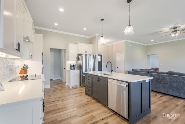 kitchen featuring appliances with stainless steel finishes, sink, a center island with sink, white cabinetry, and hanging light fixtures