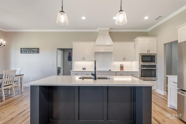 kitchen featuring pendant lighting, white cabinetry, built in microwave, and stainless steel oven