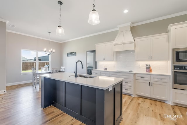 kitchen featuring sink, white cabinets, oven, and decorative light fixtures