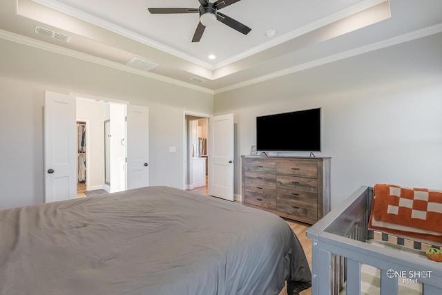 bedroom with a tray ceiling, ceiling fan, light wood-type flooring, and ornamental molding