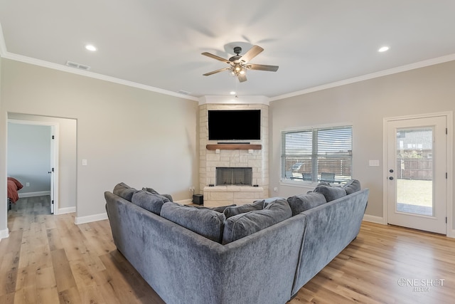 living room with a fireplace, light hardwood / wood-style flooring, ceiling fan, and crown molding