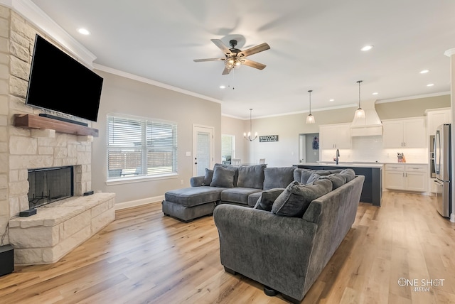 living room with a stone fireplace, ceiling fan, crown molding, and light hardwood / wood-style floors