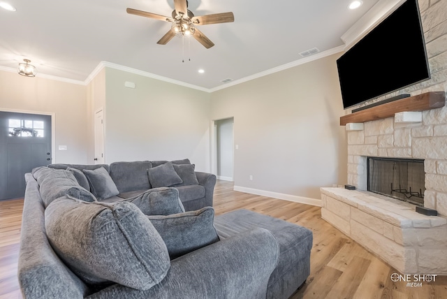 living room featuring ceiling fan, a fireplace, crown molding, and light wood-type flooring