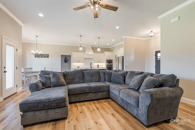 living room with crown molding, sink, light hardwood / wood-style floors, and ceiling fan with notable chandelier