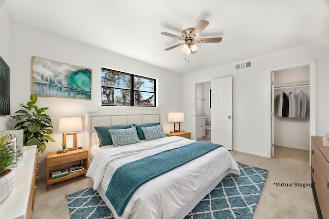 bedroom featuring ceiling fan, ensuite bathroom, light carpet, and a closet