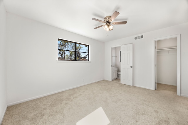 unfurnished bedroom featuring ceiling fan, ensuite bathroom, and light carpet