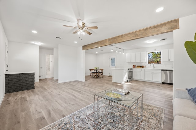 living room featuring ceiling fan, light wood-type flooring, and sink